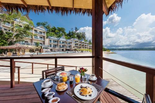 a table with food on a balcony with a view of the water at Ramada Resort by Wyndham Port Vila in Port Vila