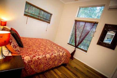 a bedroom with a bed and two windows at Mt Cotton Retreat in Mount Cotton