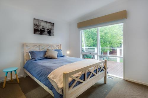 a bedroom with a bed and a large window at Cute Cottage on Cain - beach at end of street in Rye