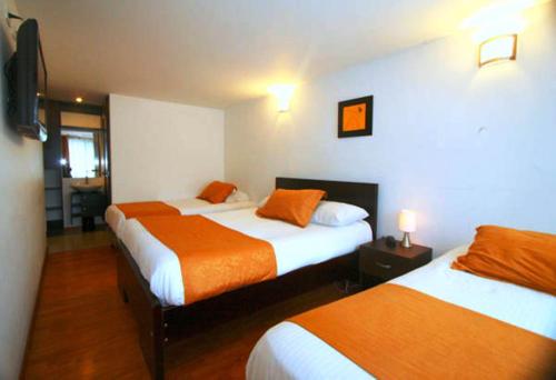 a hotel room with two beds with orange sheets at Hotel Expo Inn Embajada in Bogotá