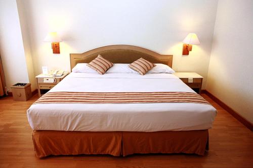 a large bed in a hotel room with two tables at Horison Ultima Bandung in Bandung