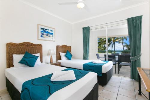 a hotel room with two beds and a balcony at Trinity Waters Boutique Beachfront in Trinity Beach