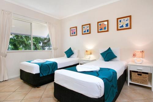 two beds in a room with a window at Trinity Waters Boutique Beachfront in Trinity Beach