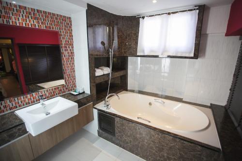 a bathroom with a tub and a sink at Grand Pink Hotel Hatyai in Hat Yai