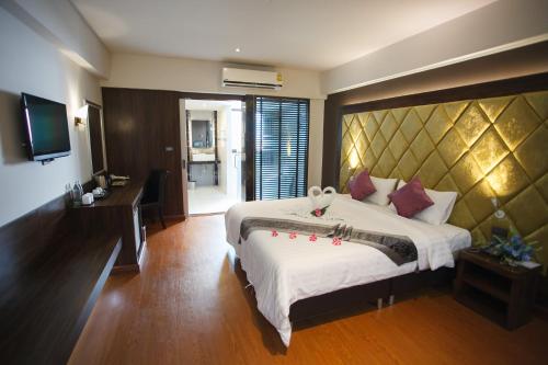 a bedroom with a large bed and a television at Grand Pink Hotel Hatyai in Hat Yai