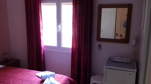 a bedroom with a bed and a mirror and a window at Kabanis Rooms in Ermoupoli