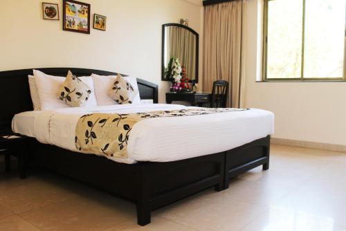 a bedroom with a large bed with white sheets and pillows at Calangute Towers - AM Hotel Kollection in Calangute