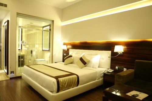 a bedroom with a large white bed and a couch at Viceroy Inn Dehradun in Dehradun
