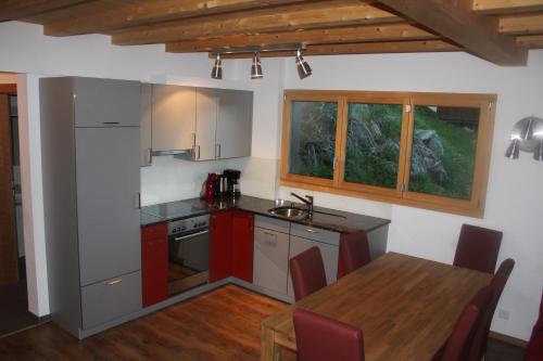 eine Küche mit roten Schränken und einem Holztisch in der Unterkunft Wakatipu-Lodge in Bettmeralp