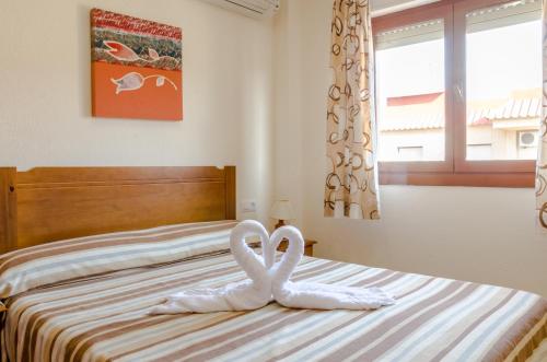 two white swans sitting on top of a bed at Apartamentos Tesy in La Manga del Mar Menor