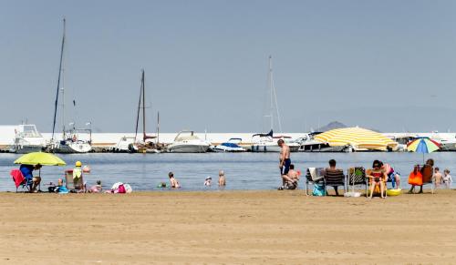 a group of people on a beach with boats in the water at Apartamentos Tesy in La Manga del Mar Menor