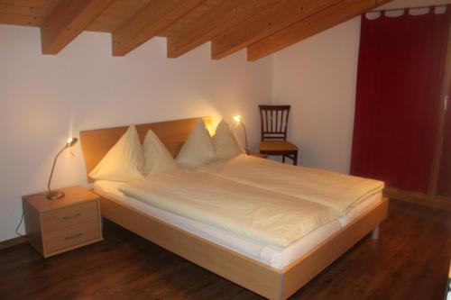 ein Schlafzimmer mit einem Bett und einem Stuhl darin in der Unterkunft Wakatipu-Lodge in Bettmeralp