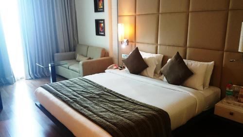 a hotel room with a large bed and a chair at Ramada by Wyndham Navi Mumbai in Navi Mumbai