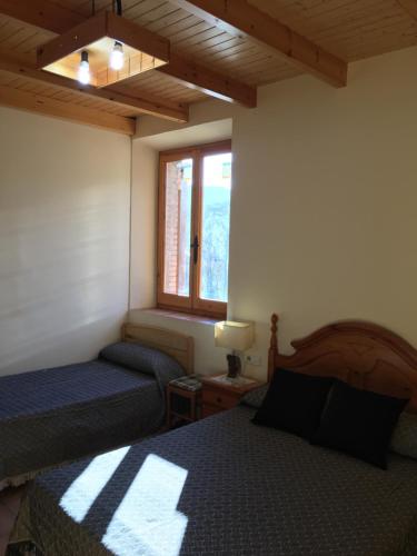 1 dormitorio con 2 camas y ventana en Santa Bárbara, en Sant Corneli de Cercs 