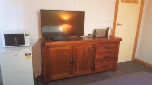 TV en la parte superior de un armario de madera junto a una nevera en Clunes Motel, en Clunes