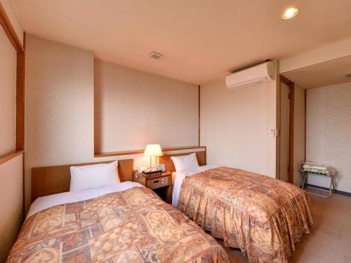a hotel room with two beds and a lamp at Hotel Shibataya in Kurihara