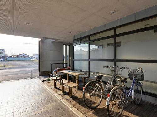 two bikes parked next to a building with a table and benches at Hotel Shibataya in Kurihara