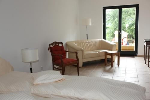 a bedroom with a bed and a chair and a couch at Lindenhof Gästehaus & Hofcafe in Kranenburg