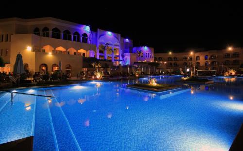 a large swimming pool in front of a building at night at Wyndham Garden Salalah Mirbat in Salalah