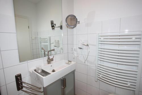 Baño blanco con lavabo y espejo en Lindenhof Gästehaus & Hofcafe, en Kranenburg