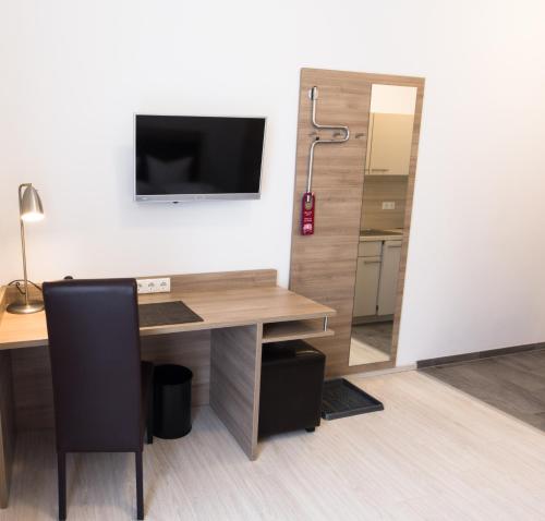 biuro z biurkiem i telewizorem na ścianie w obiekcie Aparthotel Othello w mieście Dingolfing