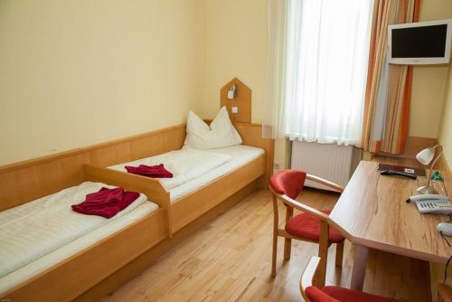 a room with two beds and a desk and a table at Gasthof Roderich Hotel in Langenzersdorf