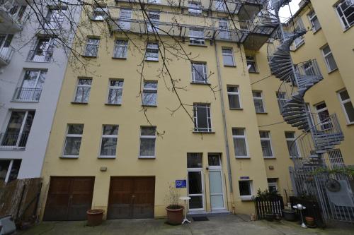 a yellow apartment building with a spiral staircase at Pension zum Lichtenberger in Berlin