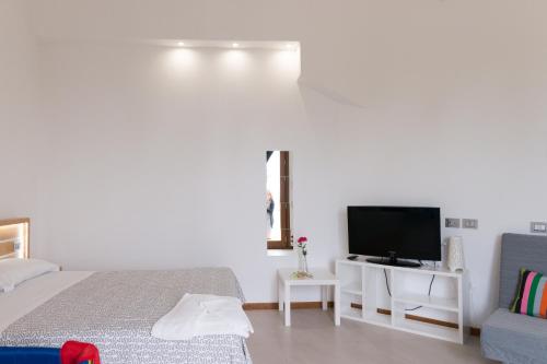 a bedroom with a bed and a tv and a couch at Lalena's Garden in Portopalo