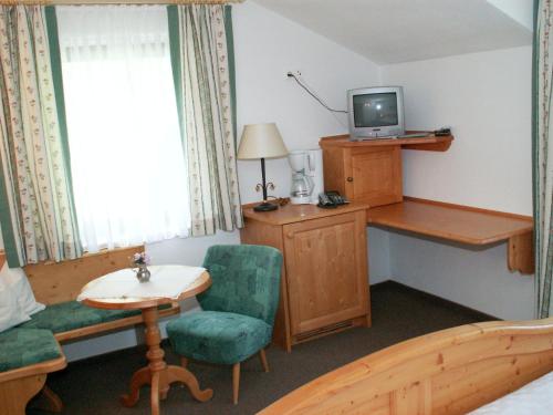 a room with a bed and a desk and a tv at Das kleine Berghotel in Liesing
