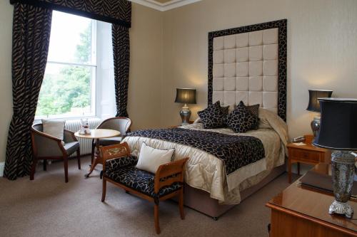 a bedroom with a bed and a table and chairs at Garvock House Hotel in Dunfermline