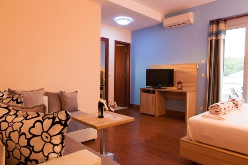 Habitación con cama, sofá y TV. en Hotel Blue Moon, en Ulcinj