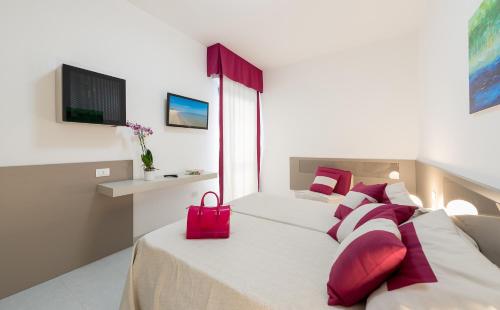 a bedroom with two beds with red pillows and a red bag at Zenit Hotel in Giulianova
