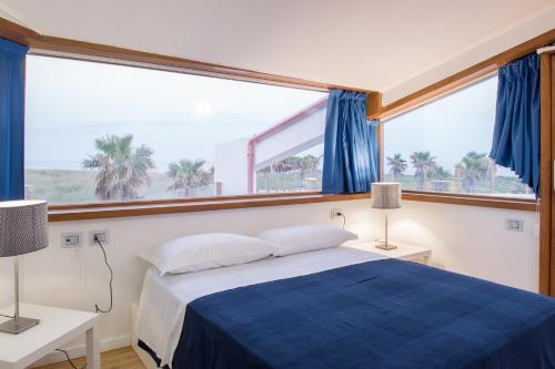 a bedroom with a blue bed and a large window at Lalena's Garden in Portopalo