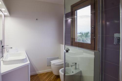 a bathroom with a toilet and a sink and a window at Lalena's Garden in Portopalo