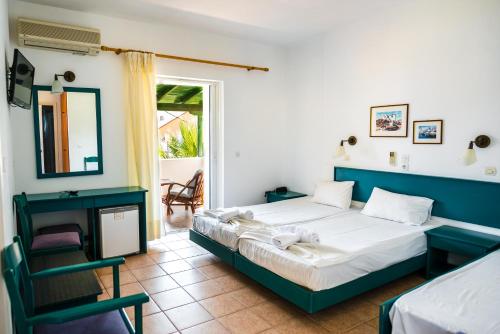 a bedroom with a bed and a chair and a window at Three Stars Beach Hotel in Moraitika