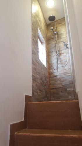 eine Dusche im Bad mit einer Steinmauer in der Unterkunft Dantes Home in Catania