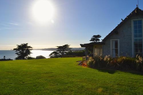 a house on a grassy hill with the ocean in the background at Ahu Ahu Beach Villas in Oakura