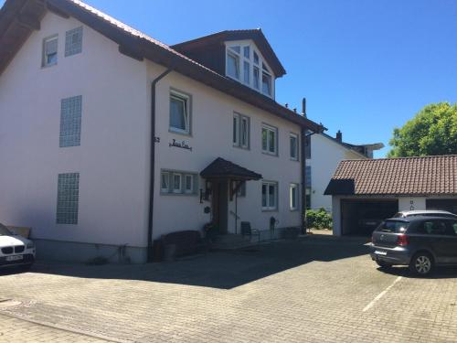 a white building with a car parked in a parking lot at Privatpension Eva in Hagnau