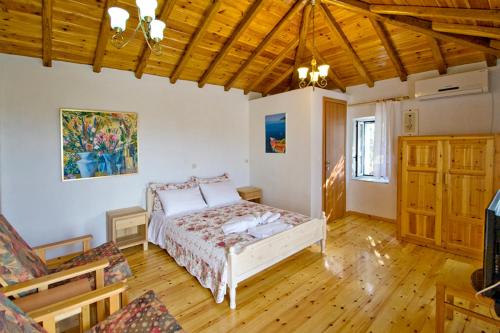 ein Schlafzimmer mit einem Bett in einem Zimmer mit Holzböden in der Unterkunft Villas Zoe in Skiathos-Stadt
