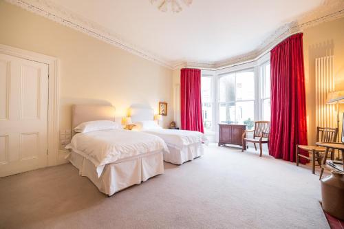 a bedroom with two beds and red curtains at The Bockery Suite 1 Chelsea in London