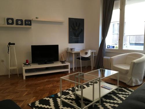 uma sala de estar com uma televisão, um sofá e uma mesa em Main Square Apartment em Zagreb