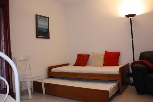 a small room with two beds and a chair at Apartamento Urbanização Aurora Rio in Vila Real de Santo António