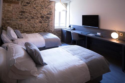 a hotel room with two beds and a desk with a television at Etoile de Pompadour in Arnac-Pompadour