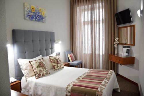 a hotel room with a bed and a window at Lusitana Hotel in Porto