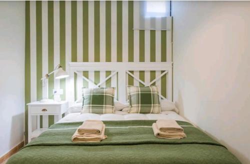 a bedroom with a bed with green and white stripes at Apartamento Alfileritos XX in Toledo