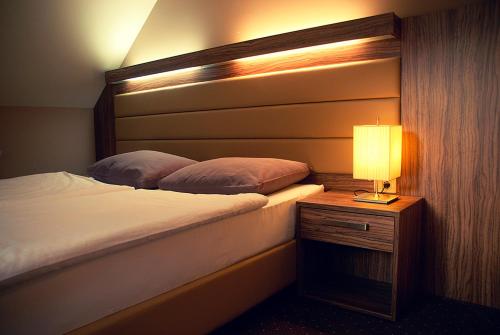 ein Schlafzimmer mit einem Bett und einer Lampe auf einem Nachttisch in der Unterkunft Hotel Opara in Trebnje