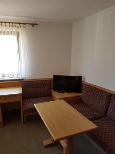 ein Wohnzimmer mit einem Sofa, einem Tisch und einem TV in der Unterkunft Gästehaus Kübler in Weissach
