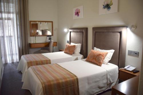 a hotel room with two beds and a desk at Lusitana Hotel in Porto