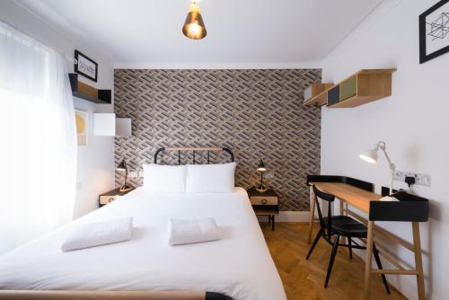 a bedroom with a white bed and a desk at The California - London Kings Cross in London