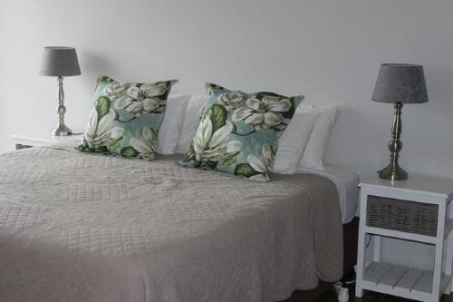 a bedroom with a bed with pillows and two lamps at Tayside Guest House in Kiddʼs Beach